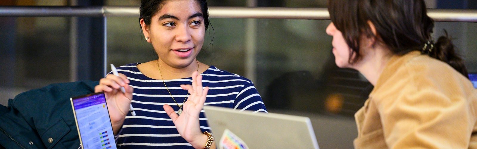 Photo of a student speaking with her mentor as they are seated in front of their computers.