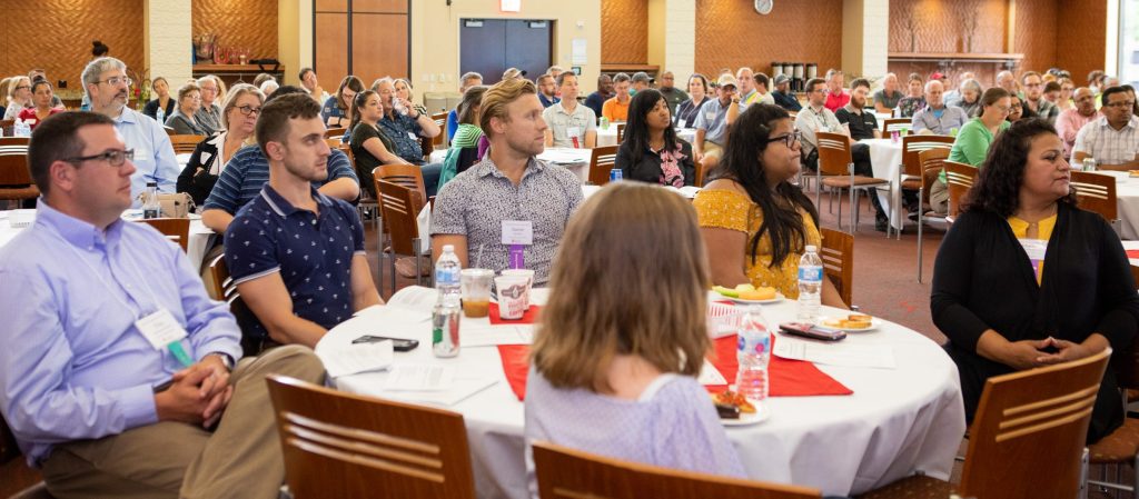 FP&M employees seated at a table in a banquet hall looking toward the right out-of-frame