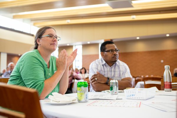 people sitting beside each other applauding at a banquet table