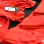 stacks of red shirts with the FP&M logo embroidered on them