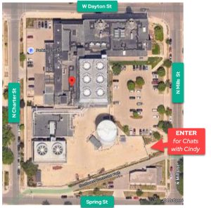 aerial photo map showing block with Charter Street Heating and Cooling Plant between Spring Street to the south, N Charter St. to the west, N Mills St. to the east, and W Dayton St to the north. "Enter for Chats with Cindy" is in a red arrow pointing to the lower right of the image, where there is a paved area off of N Mills St.
