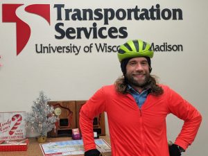 *Person poses in front of Transportation Services sign and small silver tree*