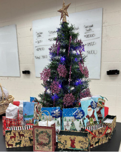 *Small tree decorated with purple lights and snowflakes, small gift bags surrounding*