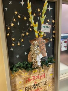 *Randolf the radioactive reindeer door decoration, black background with cutout stars, paper reindeer*