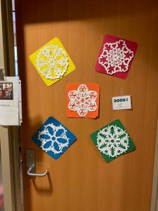 *Snowflake cutouts on red, yellow, orange, blue and greed colored paper decorate a door*