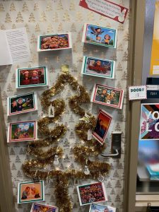 *Door decorated with tree outline in gold tinsel, door wrapped in white wrapping paper with gold trees on it, cards placed around*