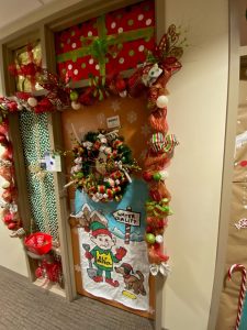 8Door decorated, elf in snow with dog and shovel, large wreath, windows wrapped as presents, and lots of ribbons, ornaments and snowflakes, via EH&S*