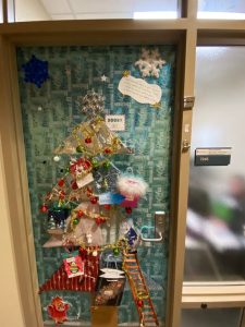 *Door wrapped in blue wrapping paper, paper tree cutout in multiple colors, snowflakes added, silver star, ornaments, etc.*