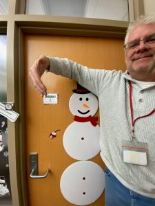 *Person poses with door decorated with paper snowman with red scarf and tophat*