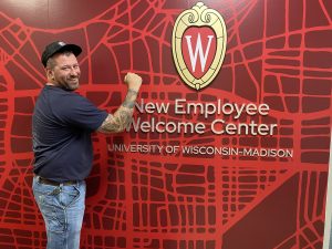 Man with his arm out in front of new employee welcome center.
