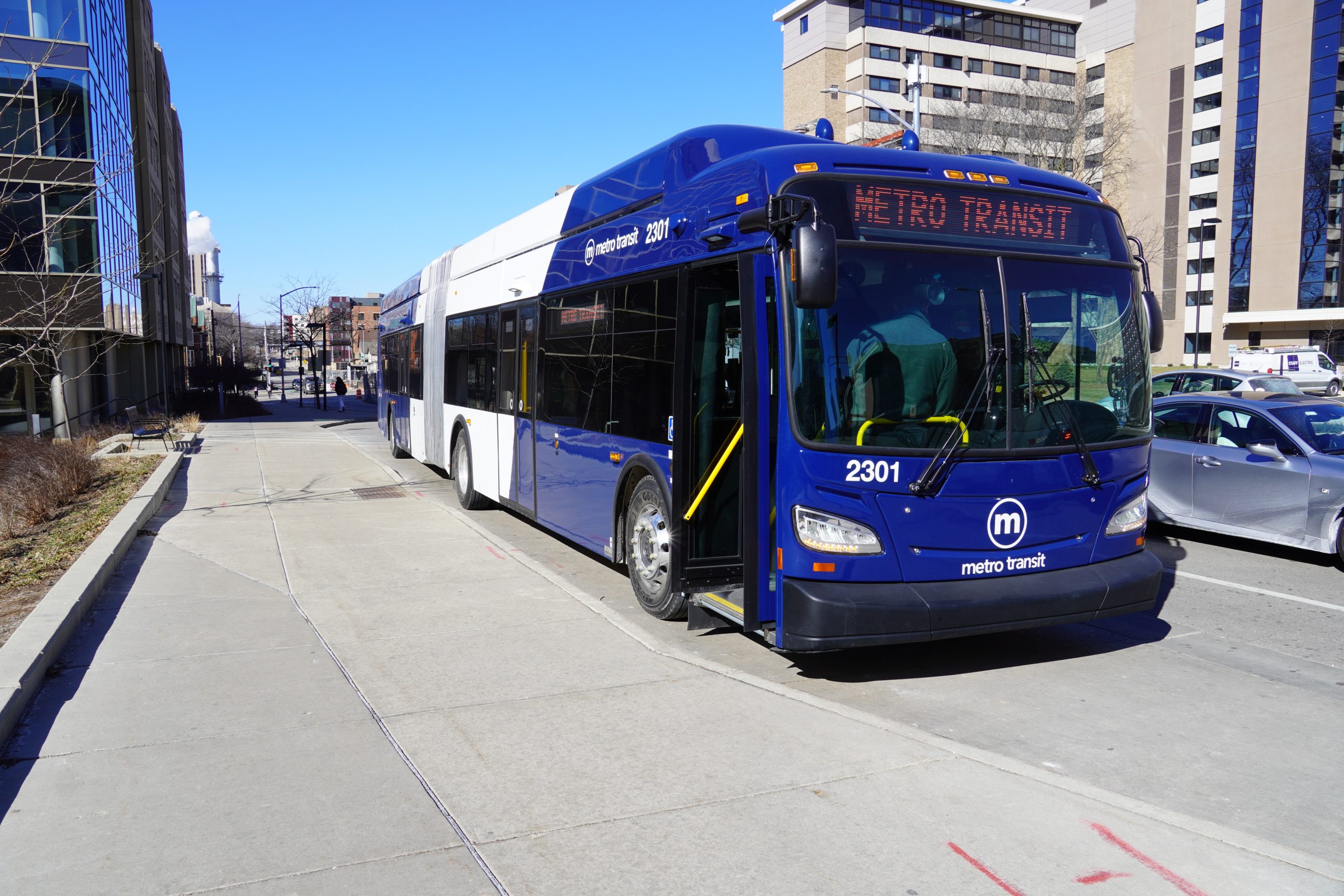 Photo of an articulated bus stopped on a busy city street on the UW-Madison campus.