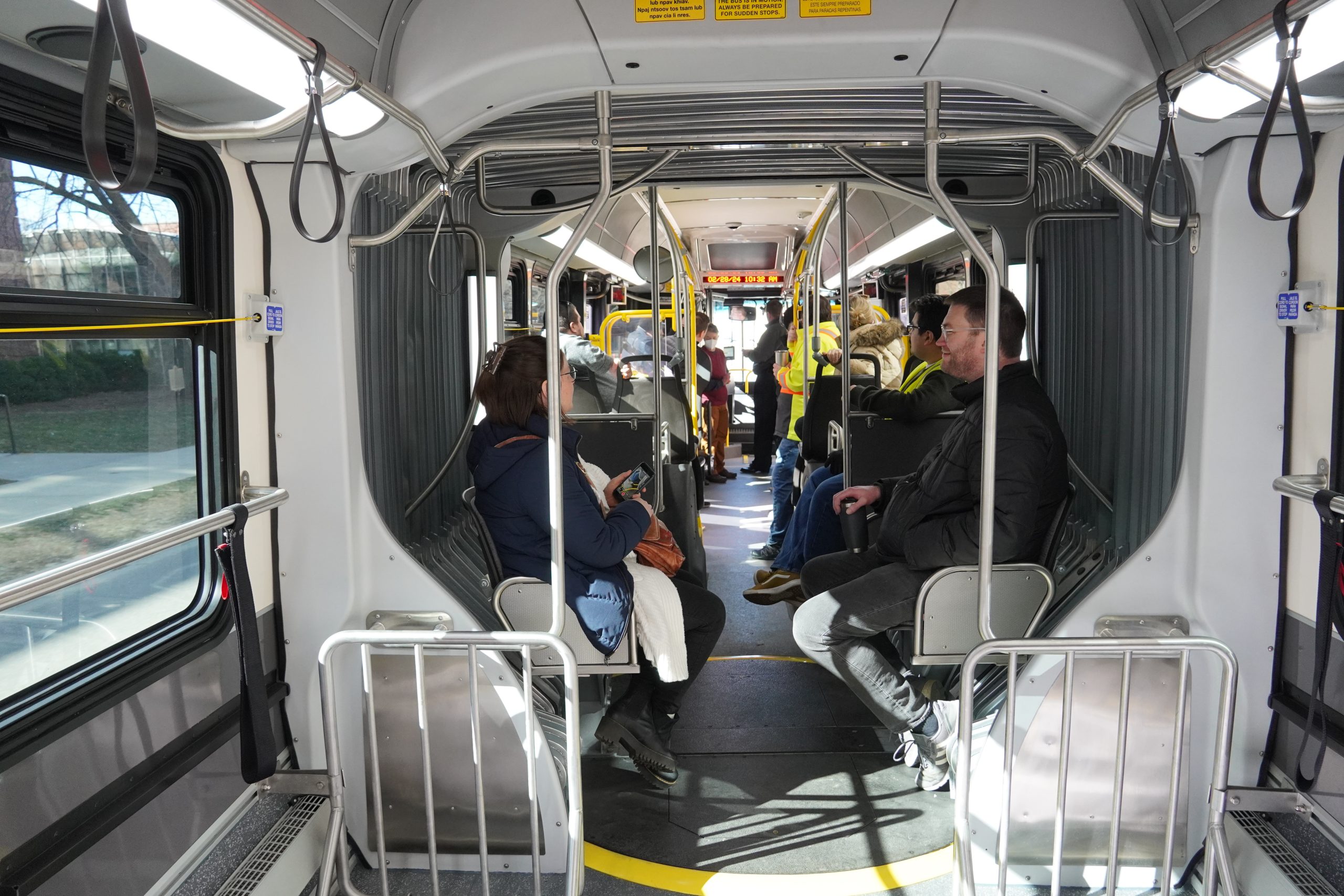 Photo of a group of people seated inside the articulated section of an articulated bus.