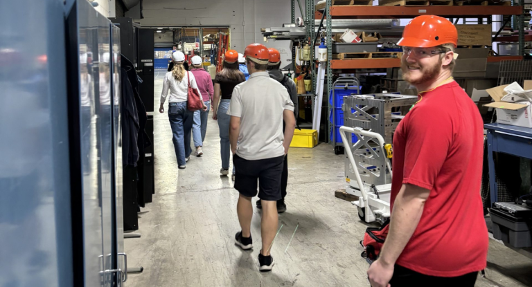 Nick, in a red hard hat and t-shirt, smiles on the tour of the recycling facility