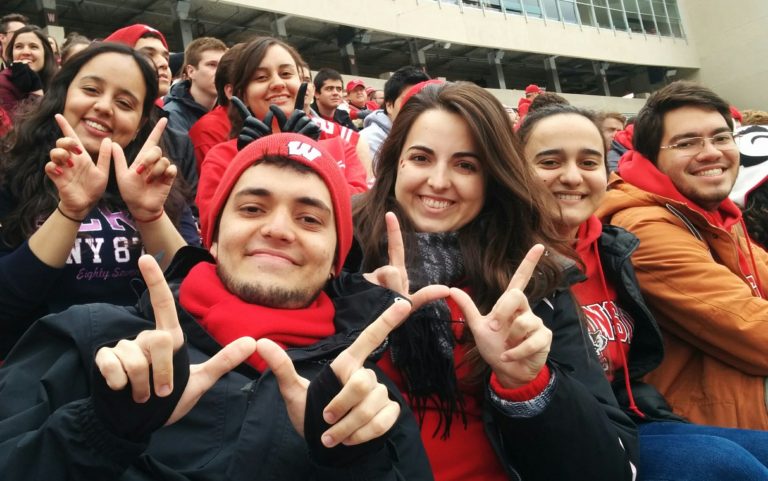 VISP students dressed in red and white make the 'W' sign with their hands at a Badger home game.