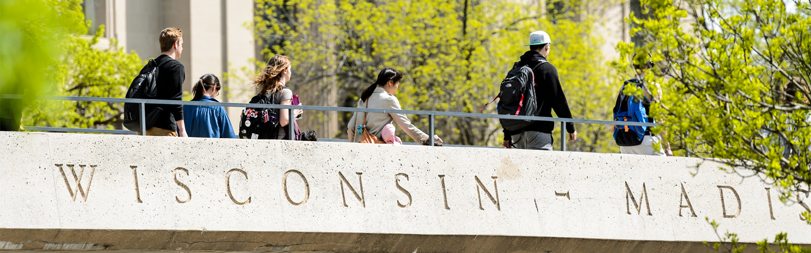 Students walk across a pedestrian bridge that crosses Park Street on the UW-Madison campus in spring time.