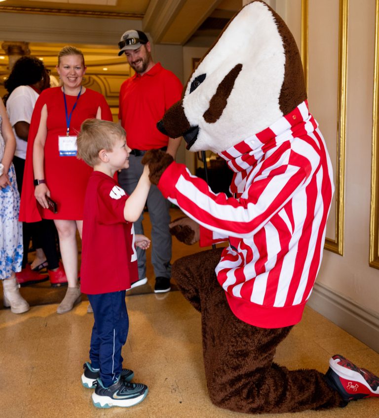 Child of returning adult student with Bucky Badger and parents looking on