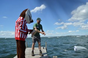 Grad Studen and Bucky Badger mascot on CFL dock on a sunny day. they are throwing out a small plankton net