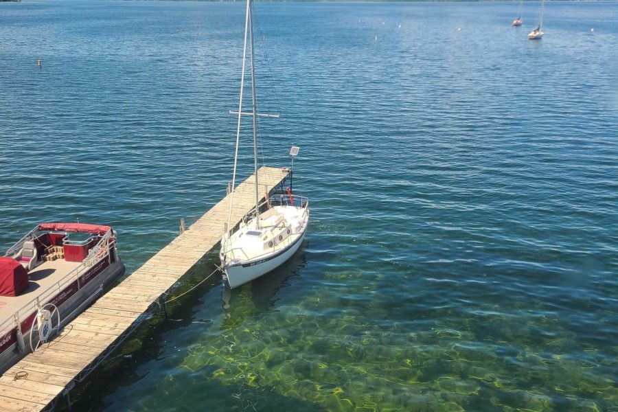 photo taken from above Hasler Lab dock showing clear water phase of Lake Mendota. Blue sky day with calm water and CFL pontoon boat on one side of dock and sail boat on other side of dock.