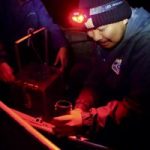 A man wearing a headlamp at night does research.