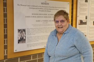Kay Emerson stands in front of her photo with Harry Waisman