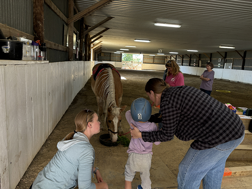 Jensen, his mom Alex Fletcher, and Hesse feed Knox carrots after the end of the session