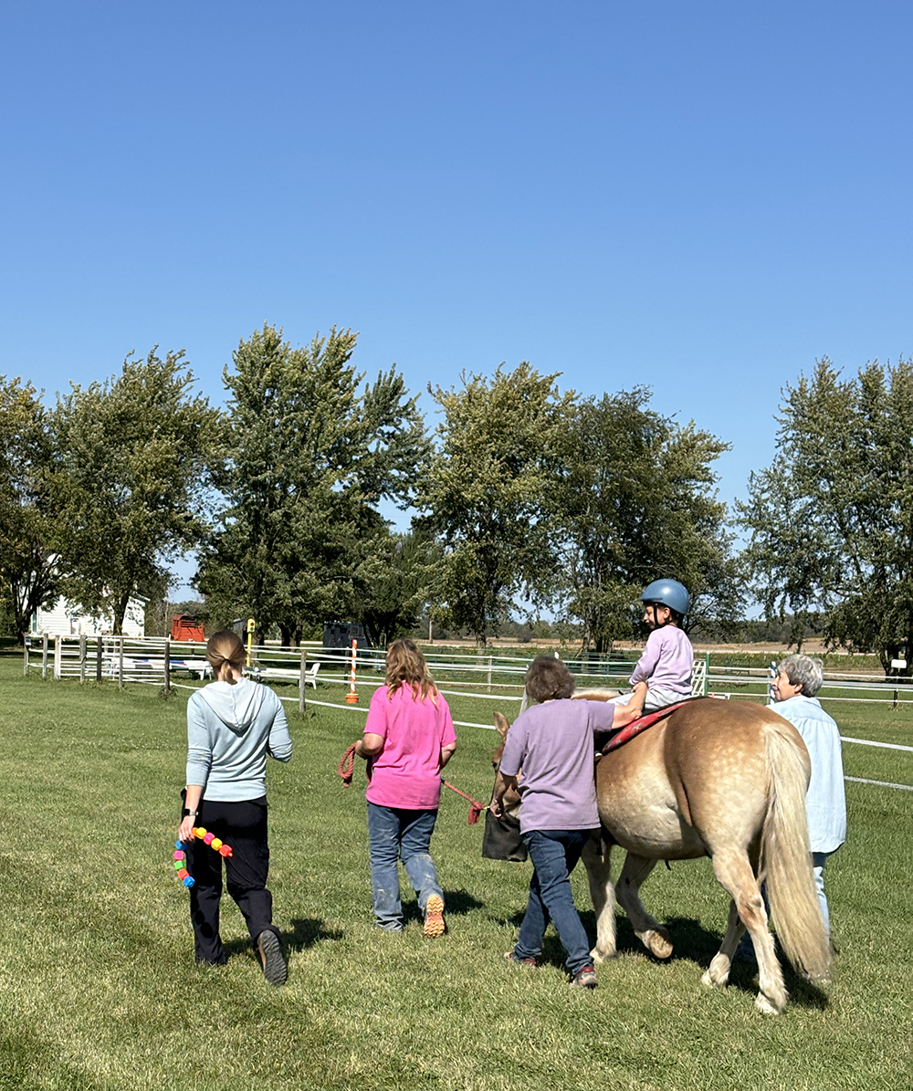 Jensen Fletcher, Elizabeth Hesse, OTD, OTR/L, Knox, and volunteers take a walk through the Three Gaits facilities