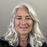 A woman with white hair smiling at the camera