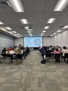 Two women present a power point about regulation in front of an audience 