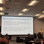 Axel Junker presets about emergency response plan talking from a podium to an audience