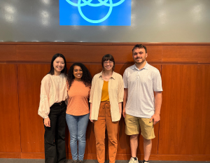 3 women and one man standing in front of a projector screening smiling