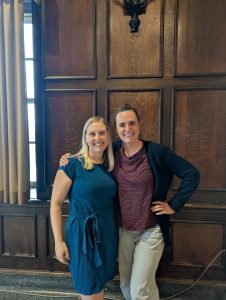 Dr. Emily Skaletski and Dr. Brittany Travers in front of a dark, wood-paneled wall.